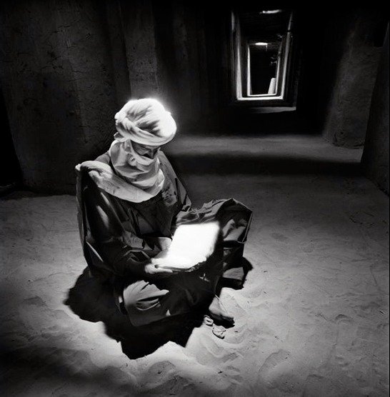 Chris Rainier - Man reading the Koran under a skylight after his prayers, Timbuktu Mosque, Mali