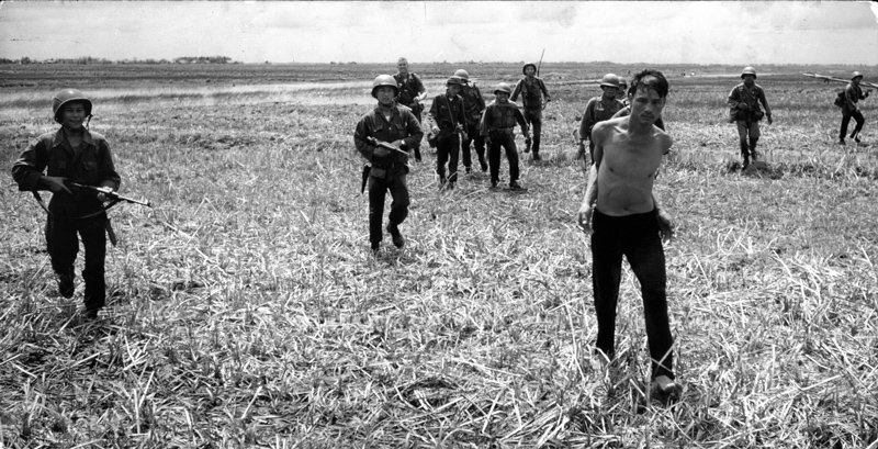 Dickey Chapelle - Vietnamese paratroopers escort a Vietcong suspect to a waiting helicopter after catching him with Communist propaganda, Vietnam 1961