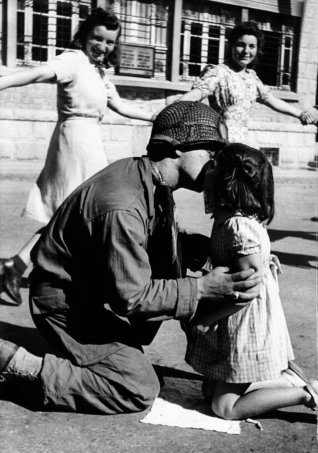 Tony Vaccaro - Kiss of liberation, Sergeant Gene Costanzo kneels to kiss a little girl during spontaneous celebrations in the main square of the town of St Briac, France 1944