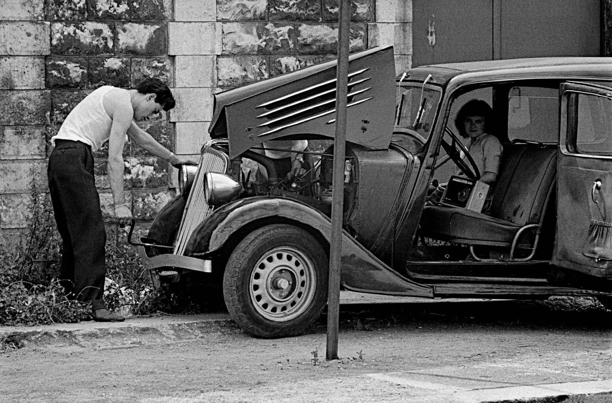 Frank Horvat - 1959, banlieue de Paris, homme qui répare sa voiture
