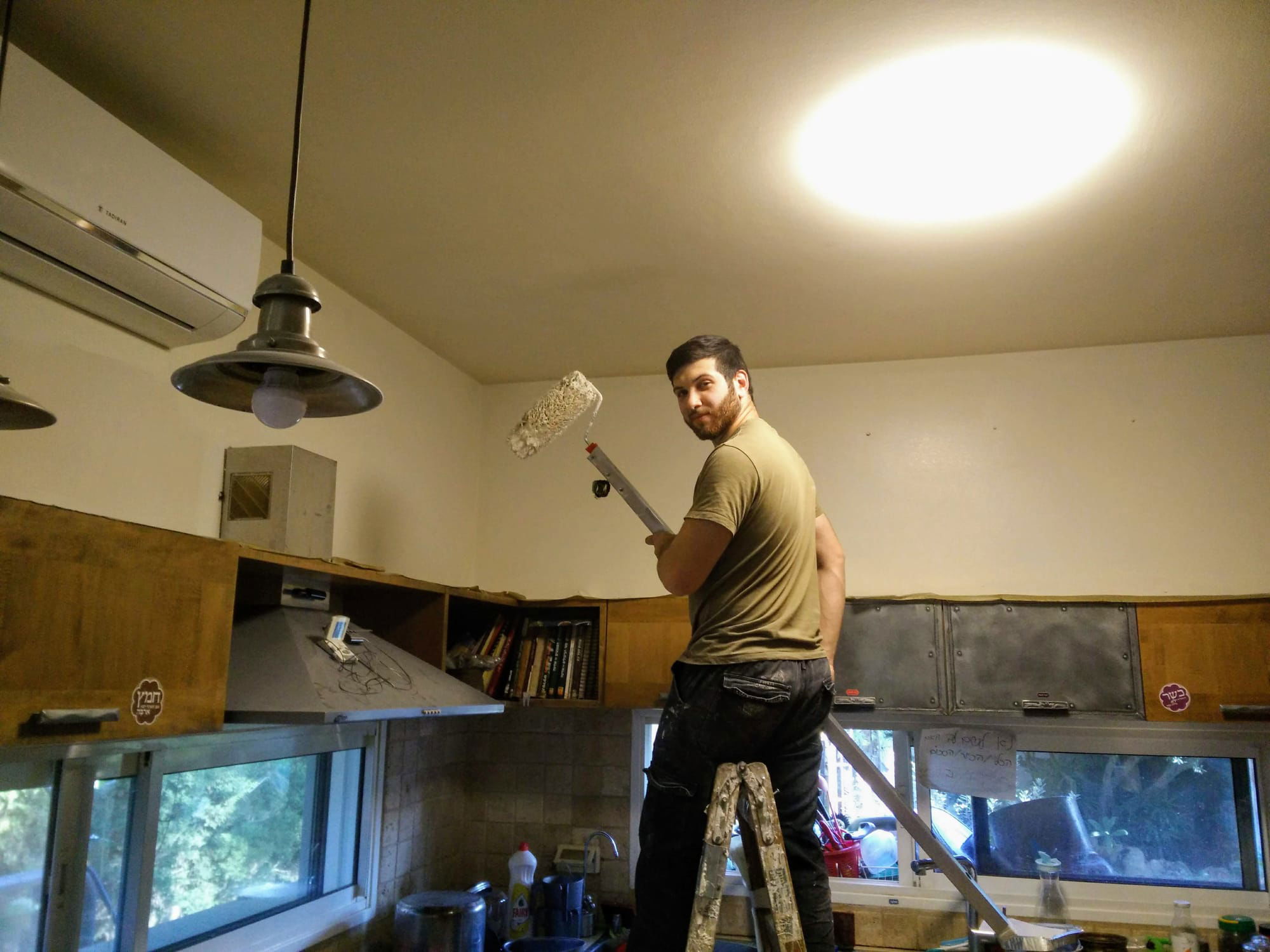 יאיר אדר על הסולם צובע את הקירות במטבח
