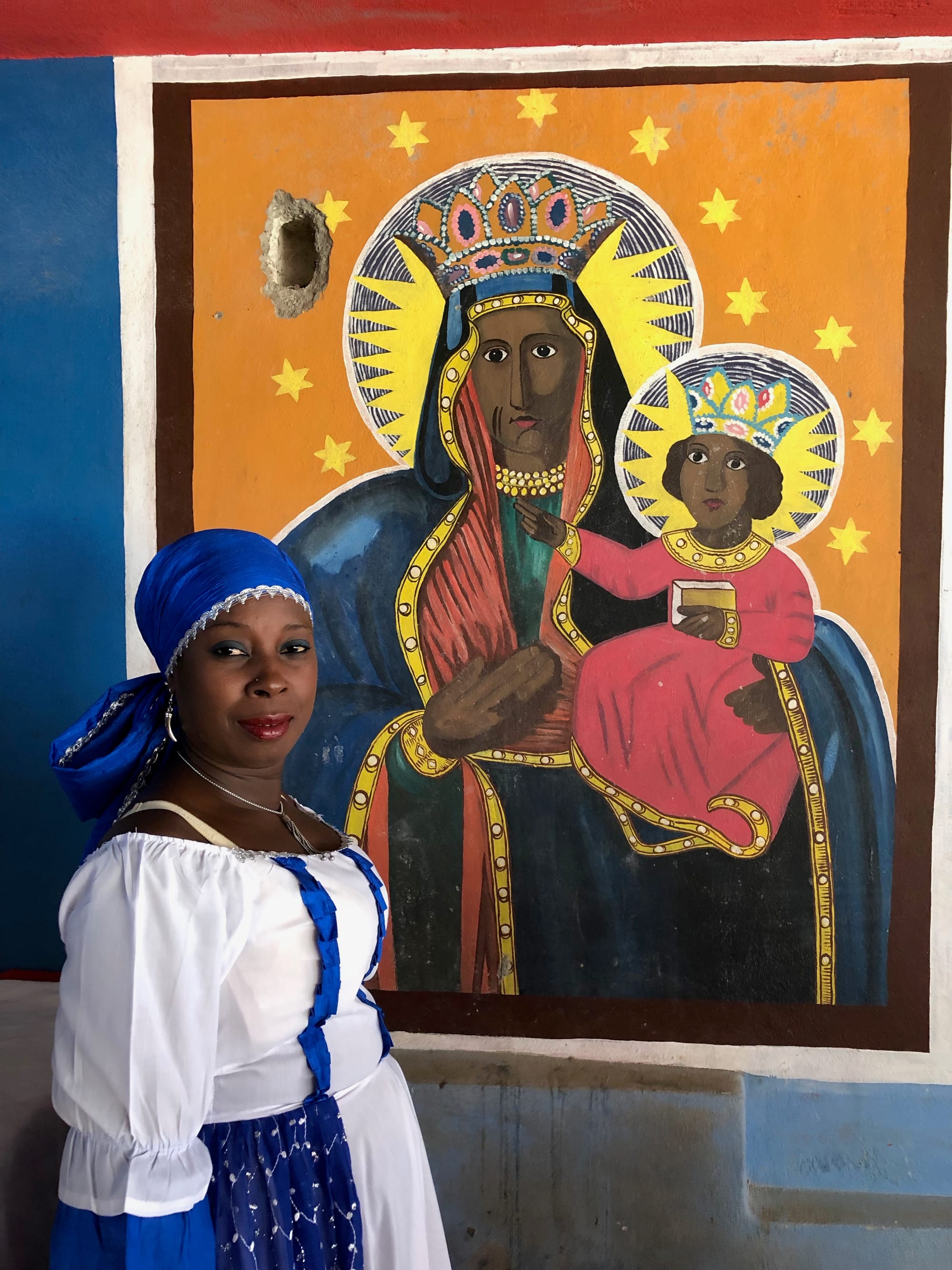 Dancer near portrait of Ezili Danto, fierce protector of children.
