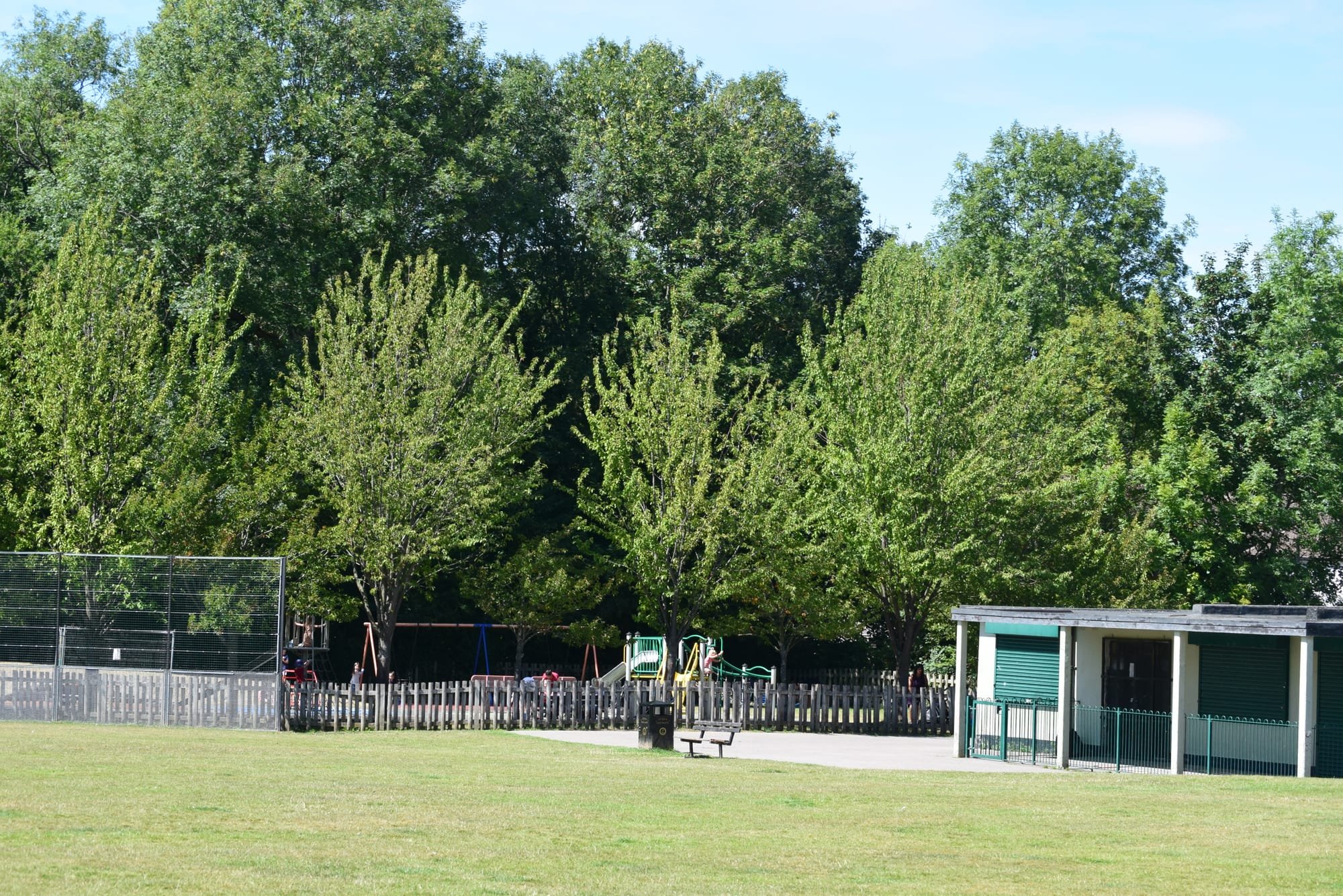 The football pavillion and preschool are between the car park and the playground