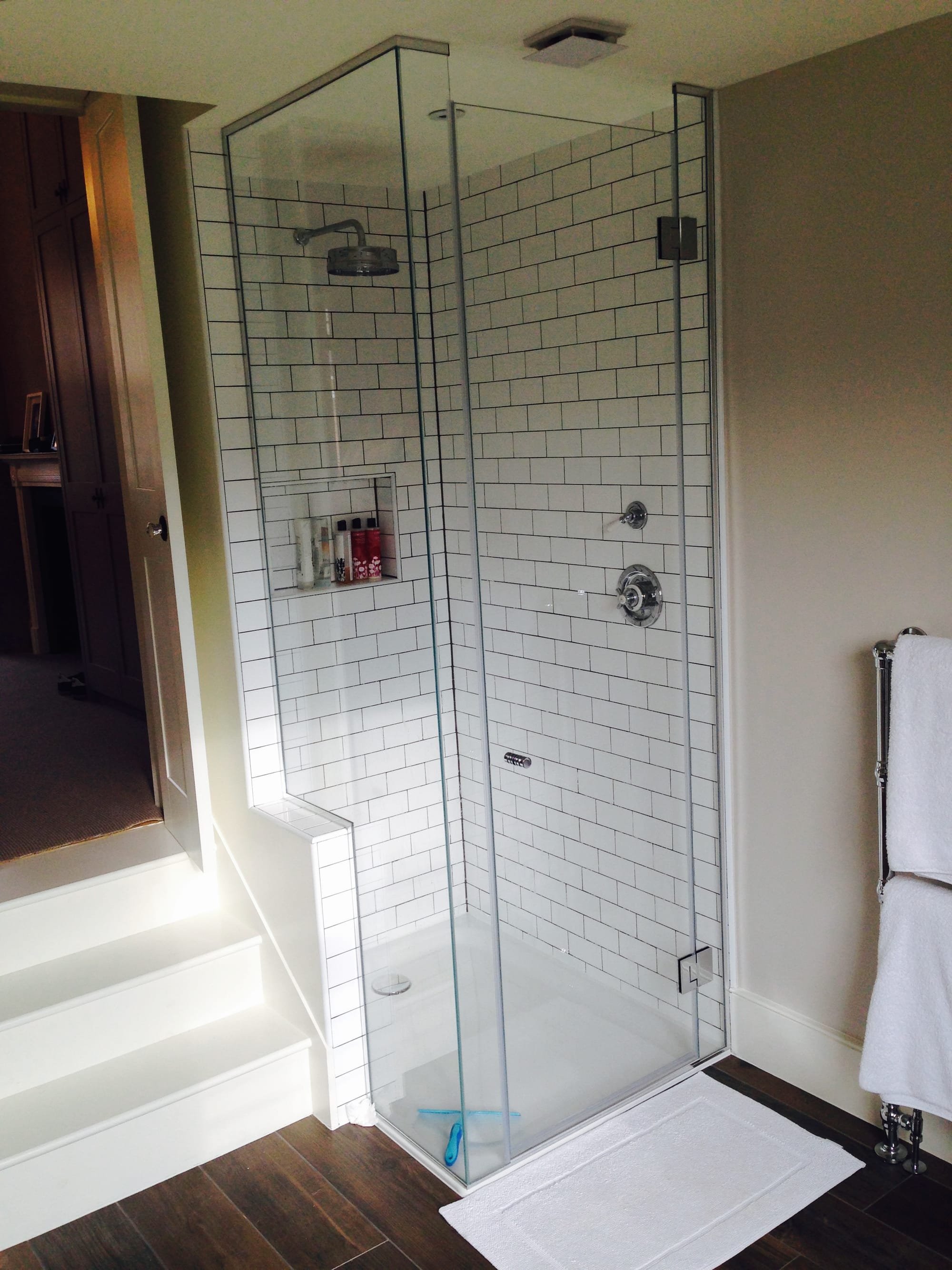 Metro tiles with contrast grout and bespoke glass shower screen to this split level master en-suite in SW17