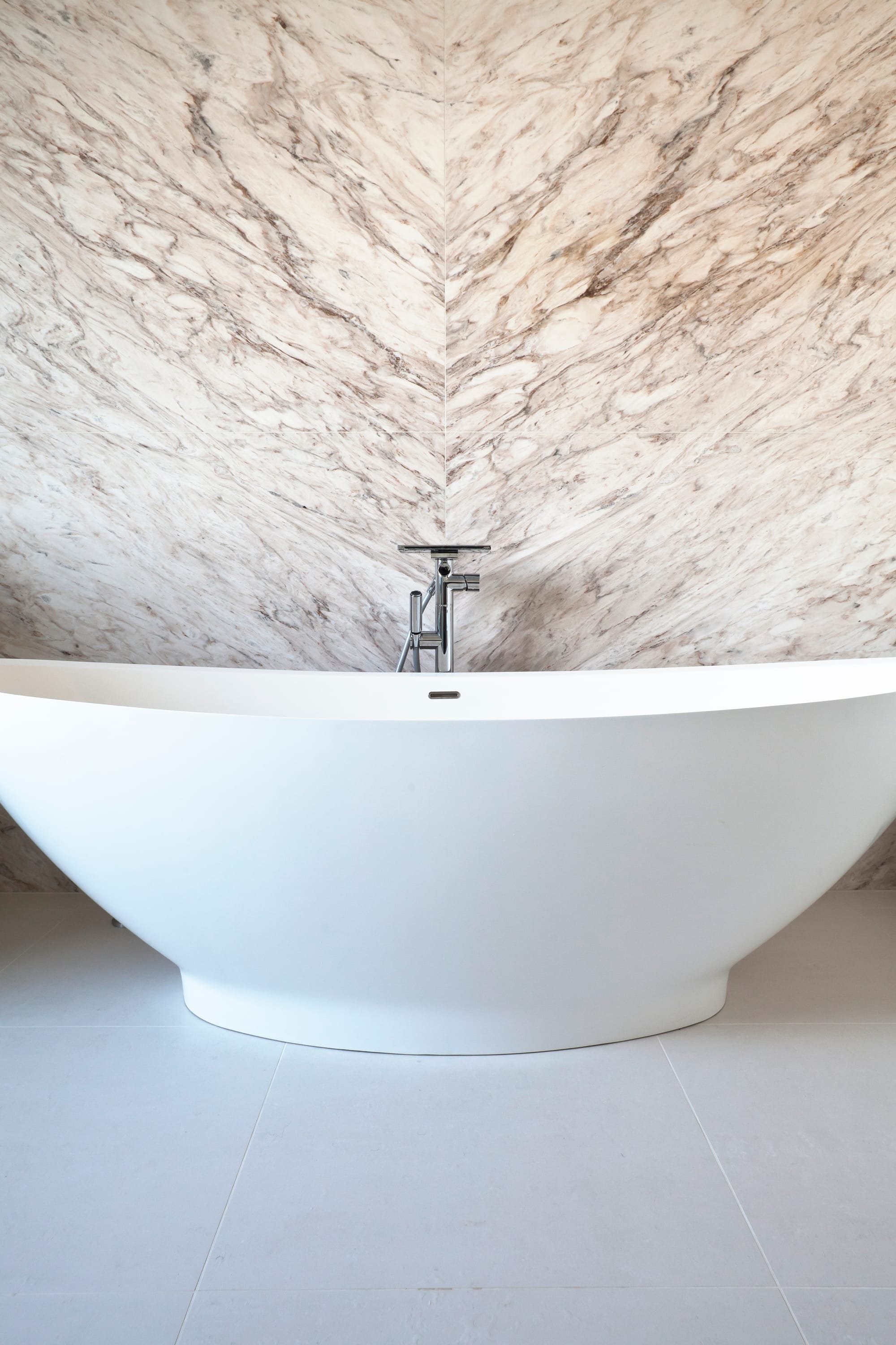 Simply stunning book matched marble forms feature wall behind this free standing bath in Wandsworth SW12