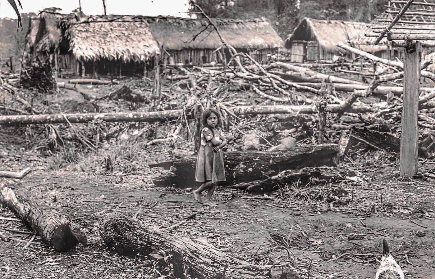 44. Niña indígena posa ante su aldea arrasada por el ejército.